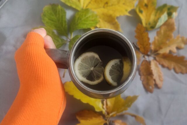 Alee pietonală într-un parc, cu frunze de toamnă și bănci de lemn pe margine